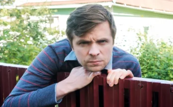 A man leaning over a wooden fence, scowling | Source: Shutterstock