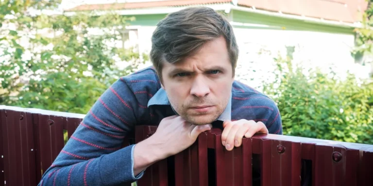 A man leaning over a wooden fence, scowling | Source: Shutterstock