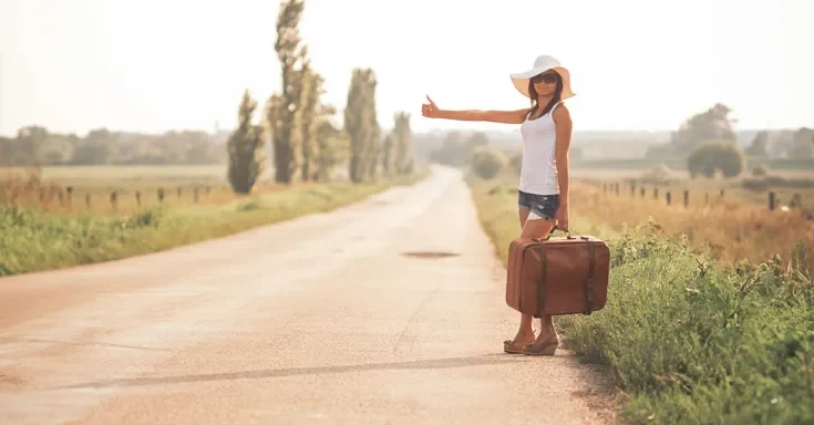 Young woman with a suitcase on a road | Source: Shutterstock