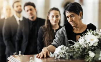 A woman placing her hand on the coffin during a funeral service | Source: Shutterstock