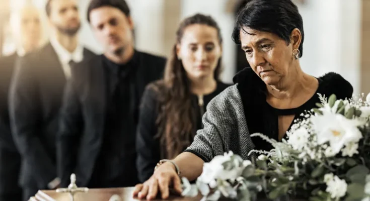 A woman placing her hand on the coffin during a funeral service | Source: Shutterstock