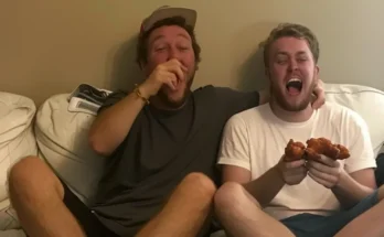 Two men eating and laughing on a couch | Source: AmoMama