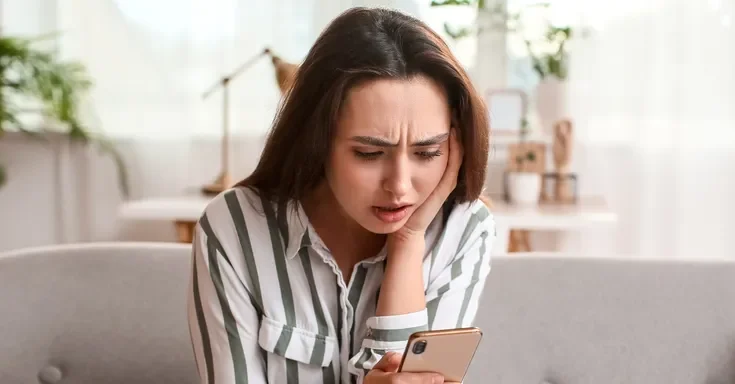 A shocked woman reading a text on her phone | Source: Shutterstock