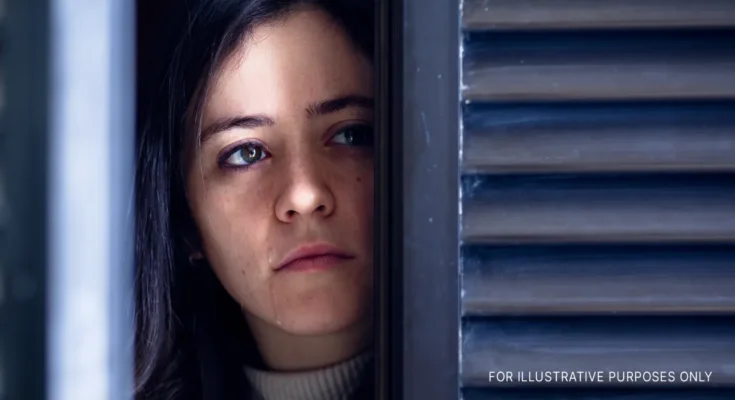 A woman watching through a door/window and crying | Source: Shutterstock