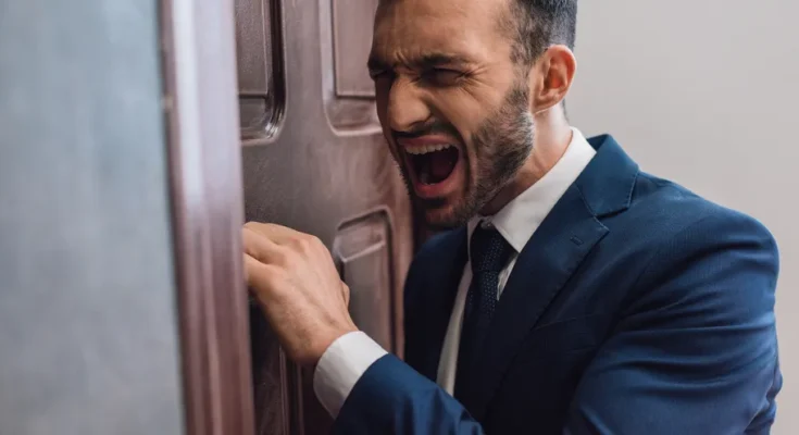 An angry man knocking on a door | Source: Shutterstock