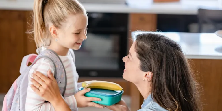 A woman handing a lunchbox to her daughter | Source: Shutterstock