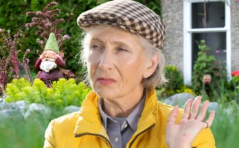 An older woman with a garden gnome in the backdrop | Source: Shutterstock