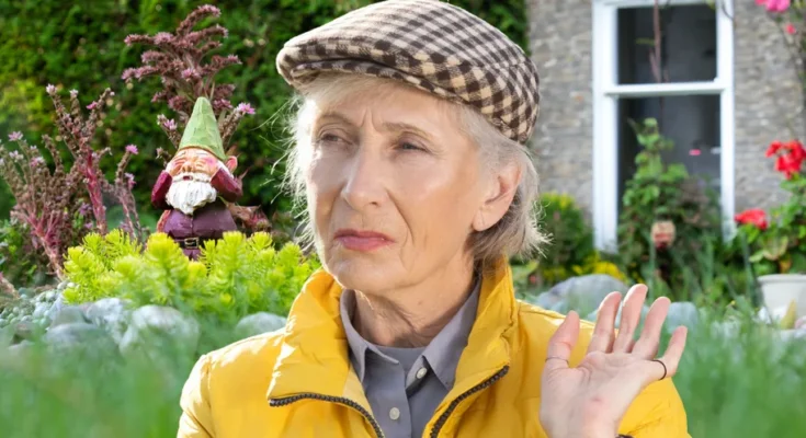 An older woman with a garden gnome in the backdrop | Source: Shutterstock