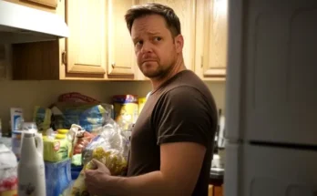 A man standing in a kitchen next to grocery items | Source: Midjourney