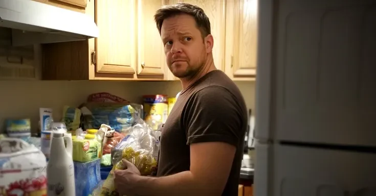 A man standing in a kitchen next to grocery items | Source: Midjourney