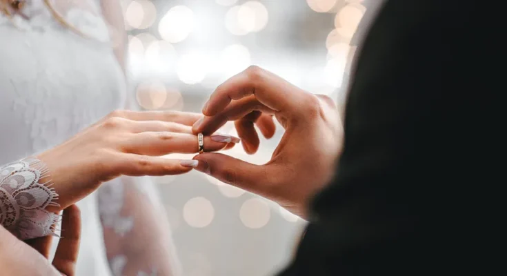 A man placing a wedding band on a women's finger| Source: Amomama