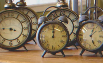 Five vintage alarm clocks on a table | Shutterstock