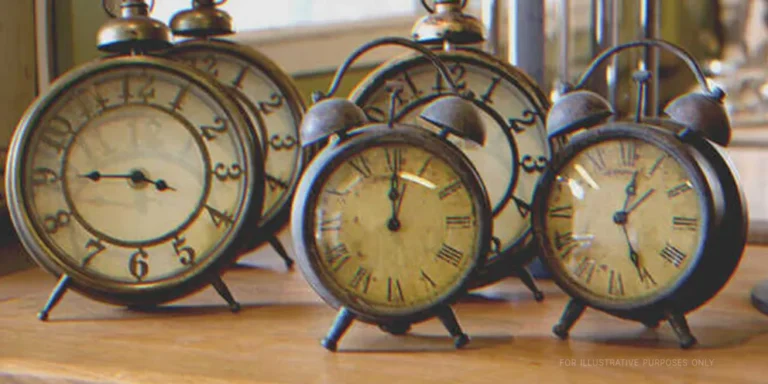 Five vintage alarm clocks on a table | Shutterstock