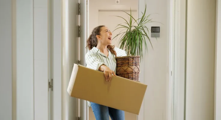 A woman carrying a box and plant | Source: Shutterstock