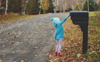 Little girl putting a letter into a mailbox | Source: Getty Images