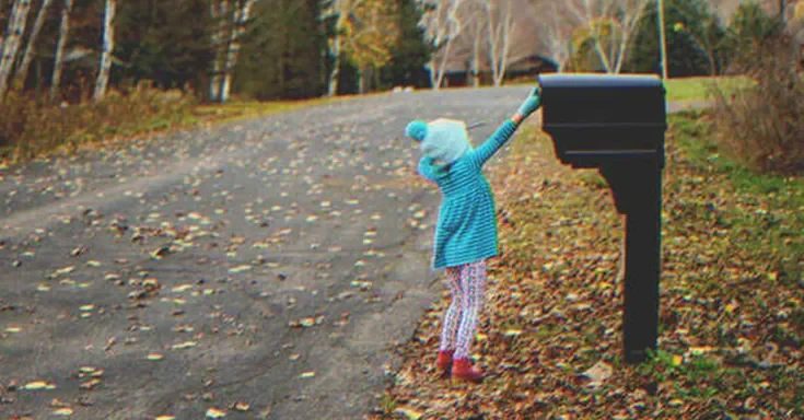 Little girl putting a letter into a mailbox | Source: Getty Images