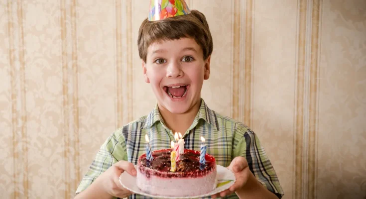 A boy holding a birthday cake | Source: Shutterstock