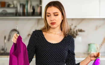 A woman holding two shirts | Source: Shutterstock