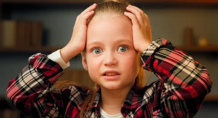 A little girl holding her head | Source: Shutterstock