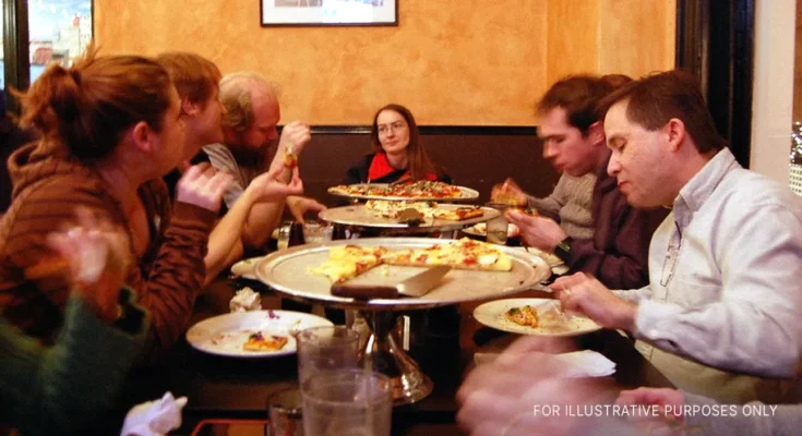 People sitting around a table and eating | Source: Flickr