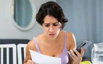 A frowning woman studying a piece of paper | Source: Shutterstock