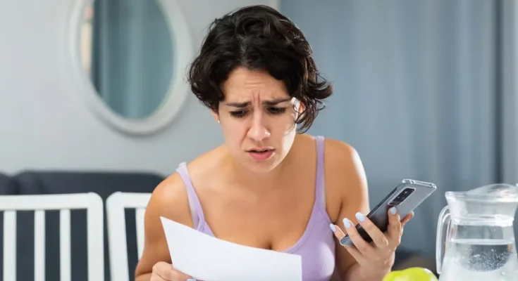 A frowning woman studying a piece of paper | Source: Shutterstock