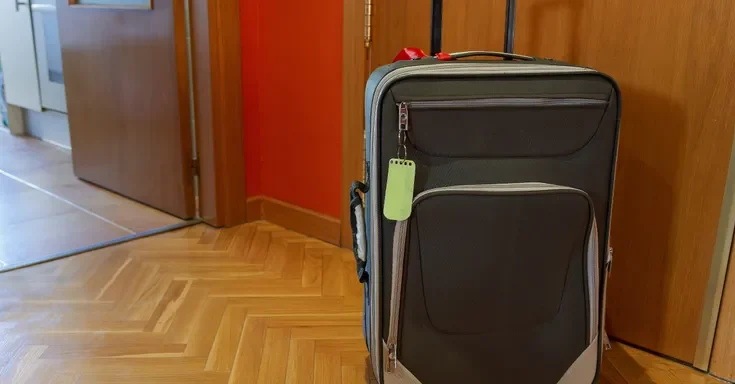 A suitcase placed outside an apartment front door | Source: Shutterstock