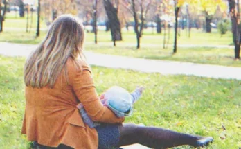 Woman with a baby sitting in the grass | Source: Shutterstock