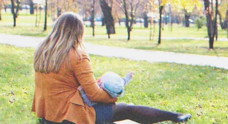 Woman with a baby sitting in the grass | Source: Shutterstock