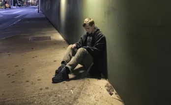 A teenage boy sitting on the street | Source: AmoMama