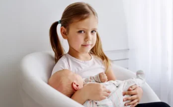 A little girl holding a baby | Source: Shutterstock