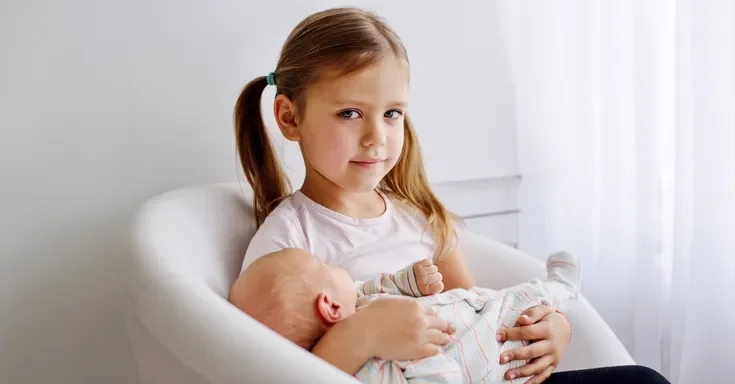 A little girl holding a baby | Source: Shutterstock