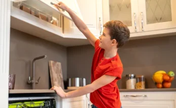 A boy opening a kitchen cupboard | Source: Shutterstock