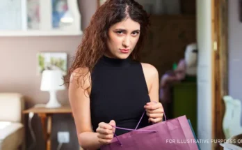 An unsure young woman holding open a paper bag | Source: Freepik.com