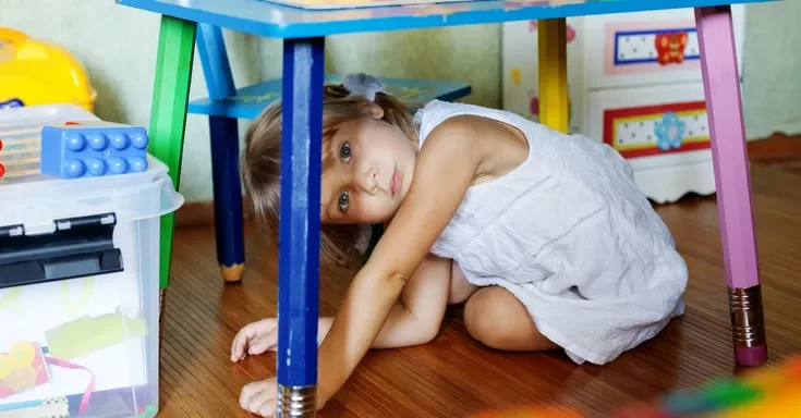 A child hiding under a table | Source: Shutterstock