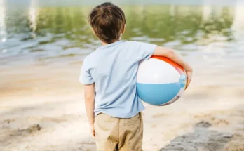 A little boy holding a ball on the beach | Source: Freepik