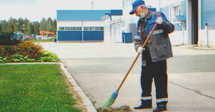 Elderly janitor sweeping outside an office | Source: Shutterstock