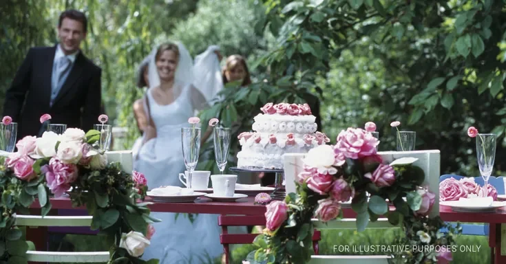 A bride and groom approach to cut the cake at a wedding reception | Source: Getty Images