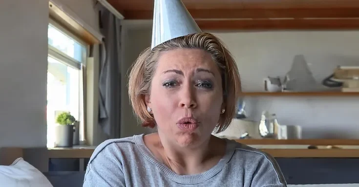 A shocked woman wearing a party hat | Source: Midjourney