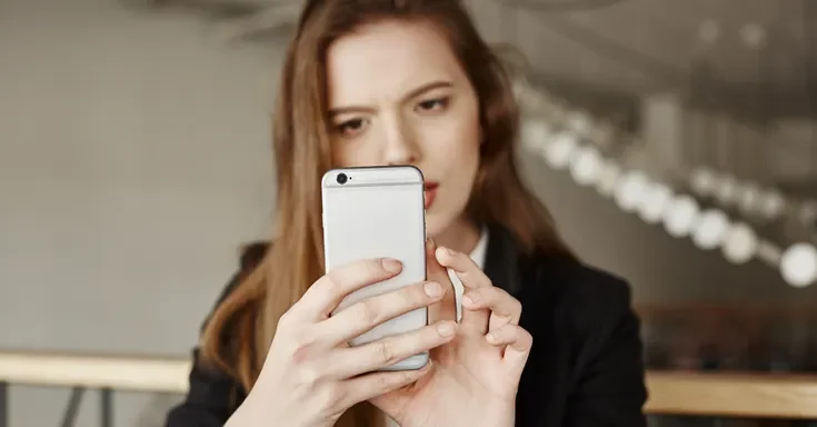 A woman frowning at her phone | Source: Freepik