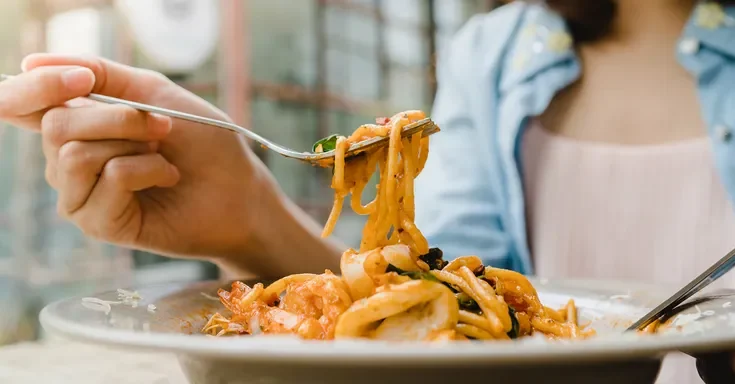 A closeup of a woman eating pasta | Source: Shutterstock