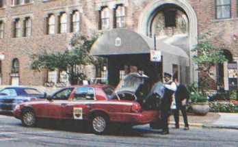 A driver getting a suitcase inside the trunk of a car parked in front of a building | Source: Shutterstock