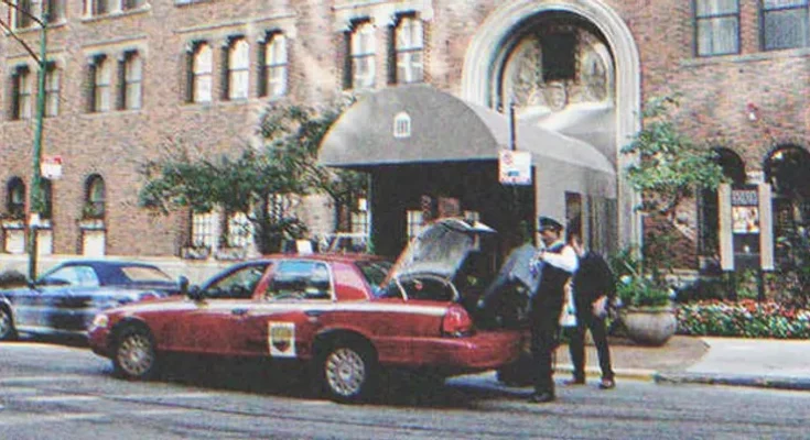 A driver getting a suitcase inside the trunk of a car parked in front of a building | Source: Shutterstock