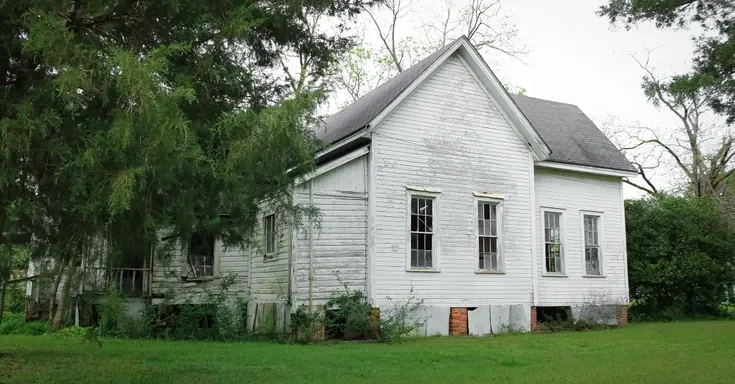 An old house surrounded by trees and a lush green lawn | Source: Shutterstock