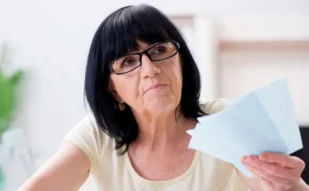 An older woman holding some papers | Source: Shutterstock