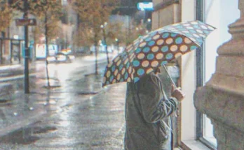 An old lady holding an umbrella and looking inside a business | Source: Shutterstock