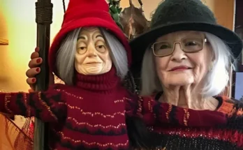 An elderly woman standing next to a witch statue on Halloween | Source: Amomama