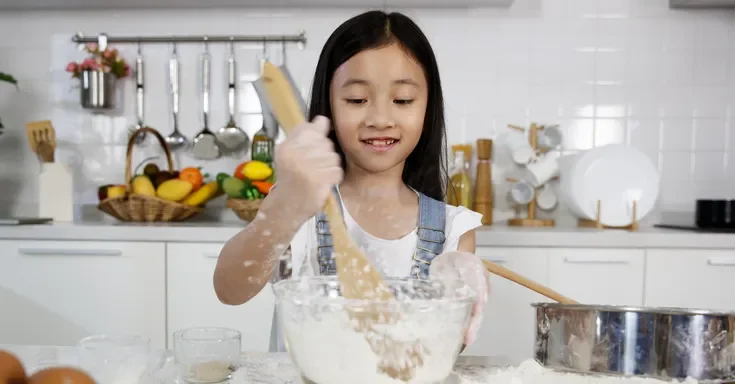 A young girl mixing flour in a bowl | Source: Shutterstock