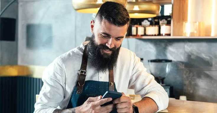 A man looking at his phone and laughing | Source: Shutterstock