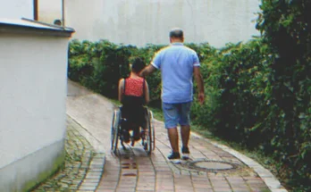 A girl in a wheelchair next to a man | Source: Shutterstock